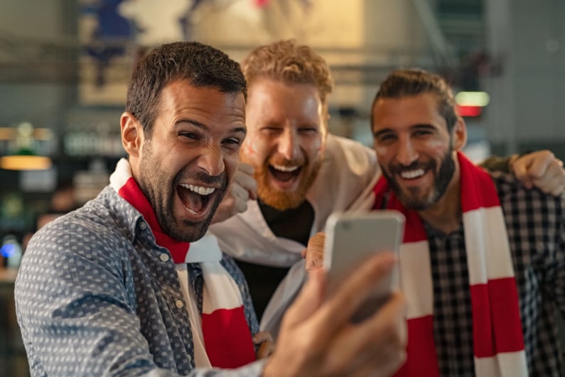 Sports fans celebrated while looking at a phone
