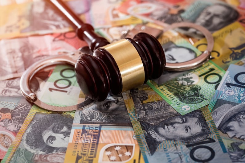 Handcuffs and gavel on top of Australian money