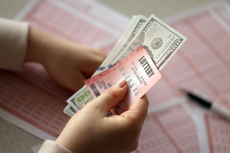 Woman holding lottery ticket and cash