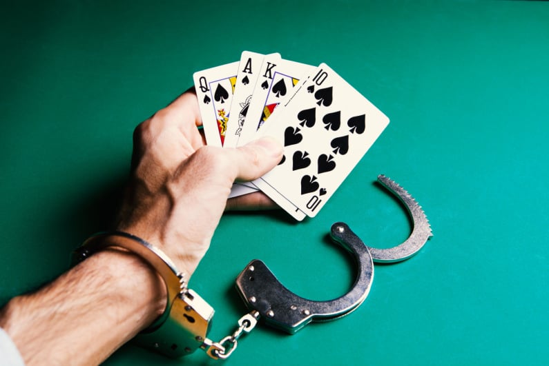 Man holding playing cards while handcuffed