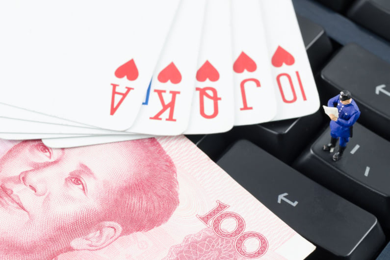 Miniature policeman on a keyboard with cards and Chinese currency
